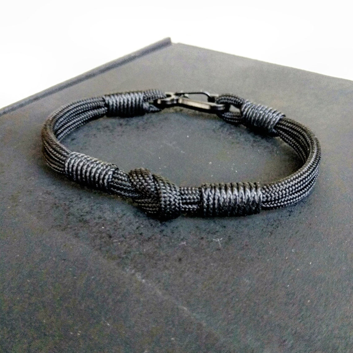 Thin military black bracelet made of paracord and carabine for men. Army style.