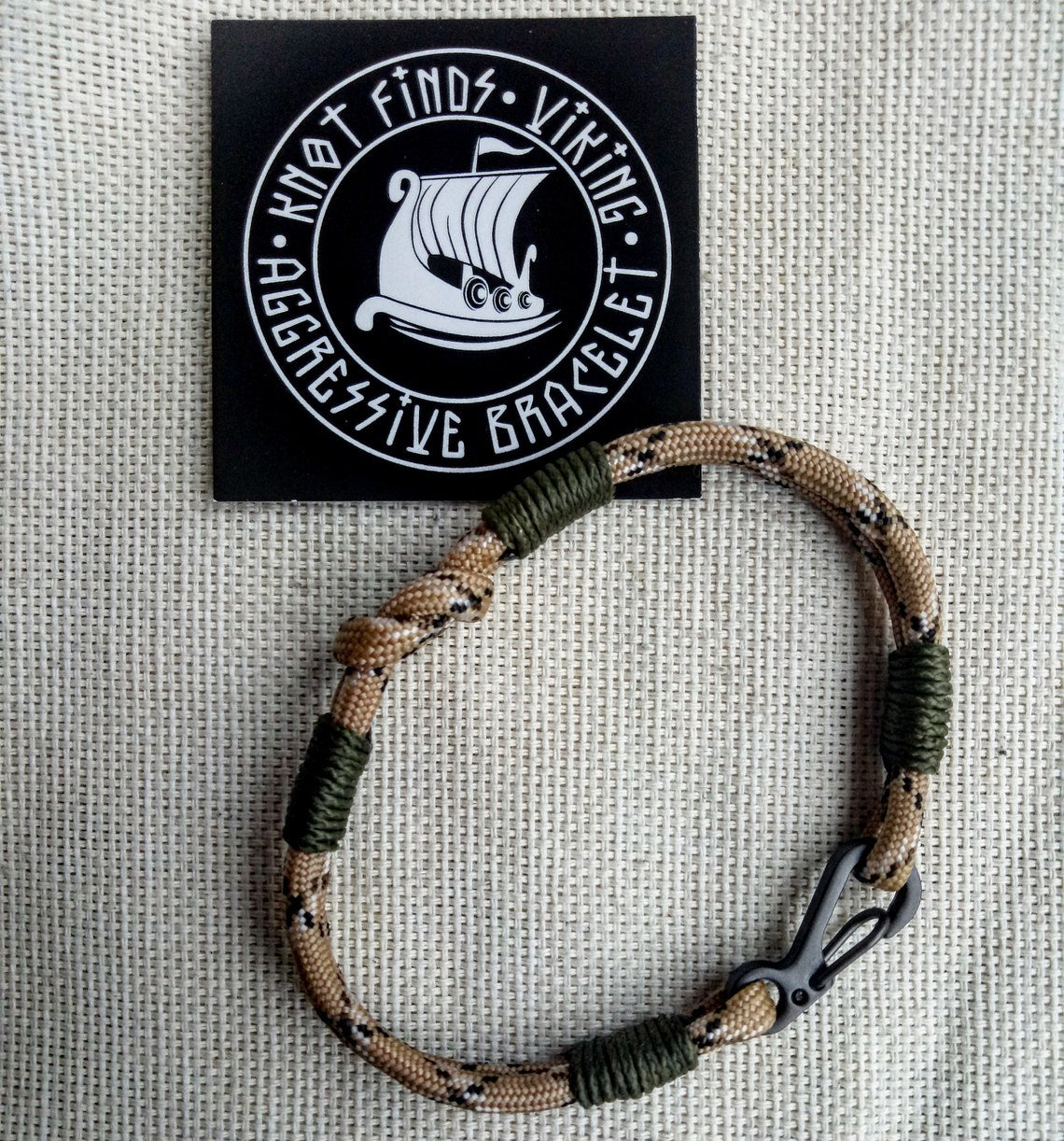 Thin military bracelet made of paracord and carabine for men. Camouflage desert camo. Army style.