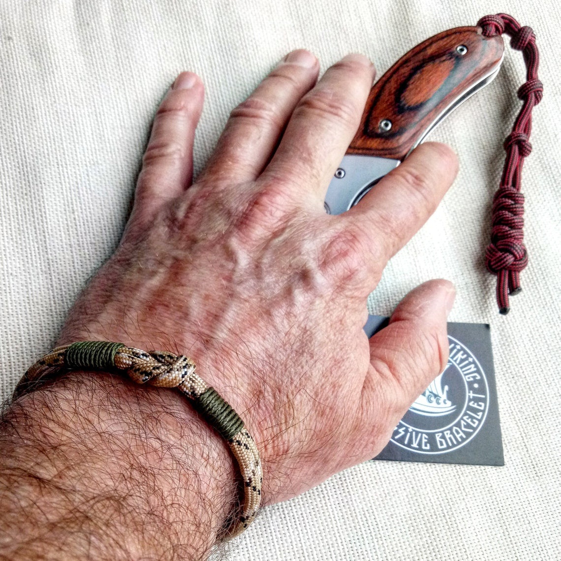 Thin military bracelet made of paracord and carabine for men. Camouflage desert camo. Army style.