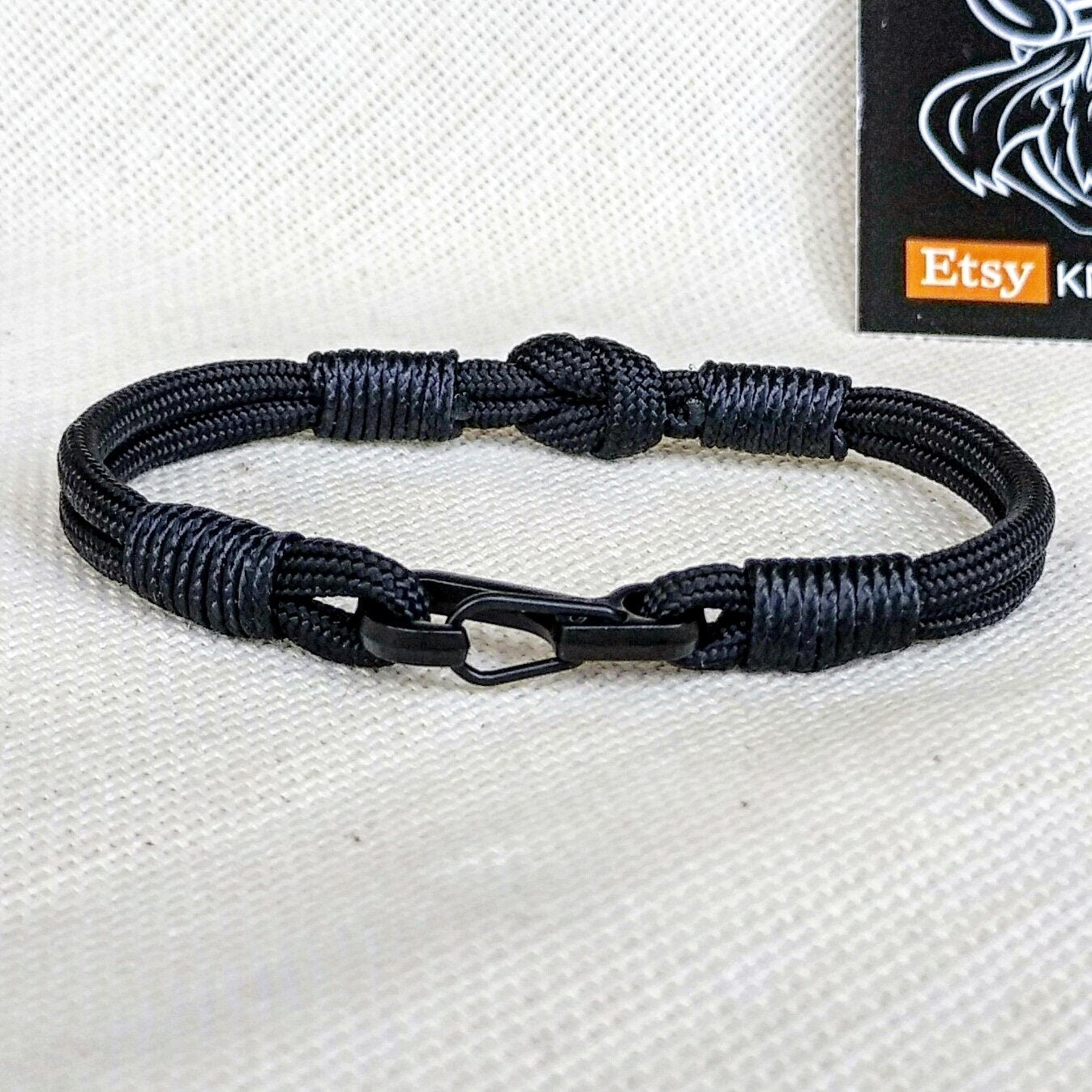 Thin military black bracelet made of paracord and carabine for men. Army style.