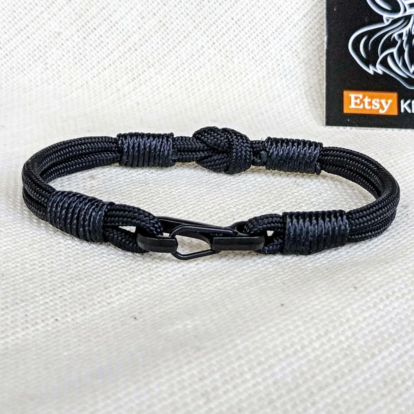 Thin military black bracelet made of paracord and carabine for men. Army style.