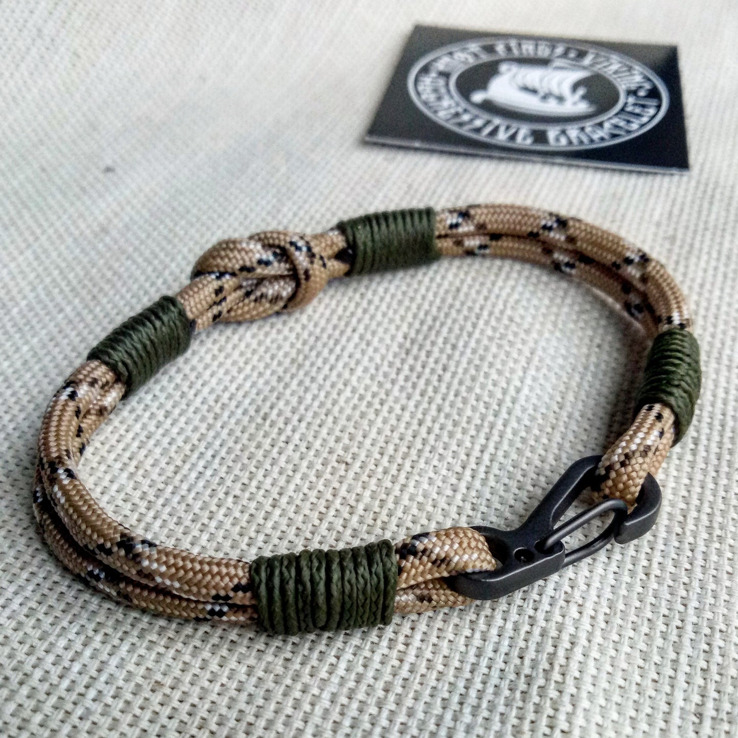 Thin military bracelet made of paracord and carabine for men. Camouflage desert camo. Army style.