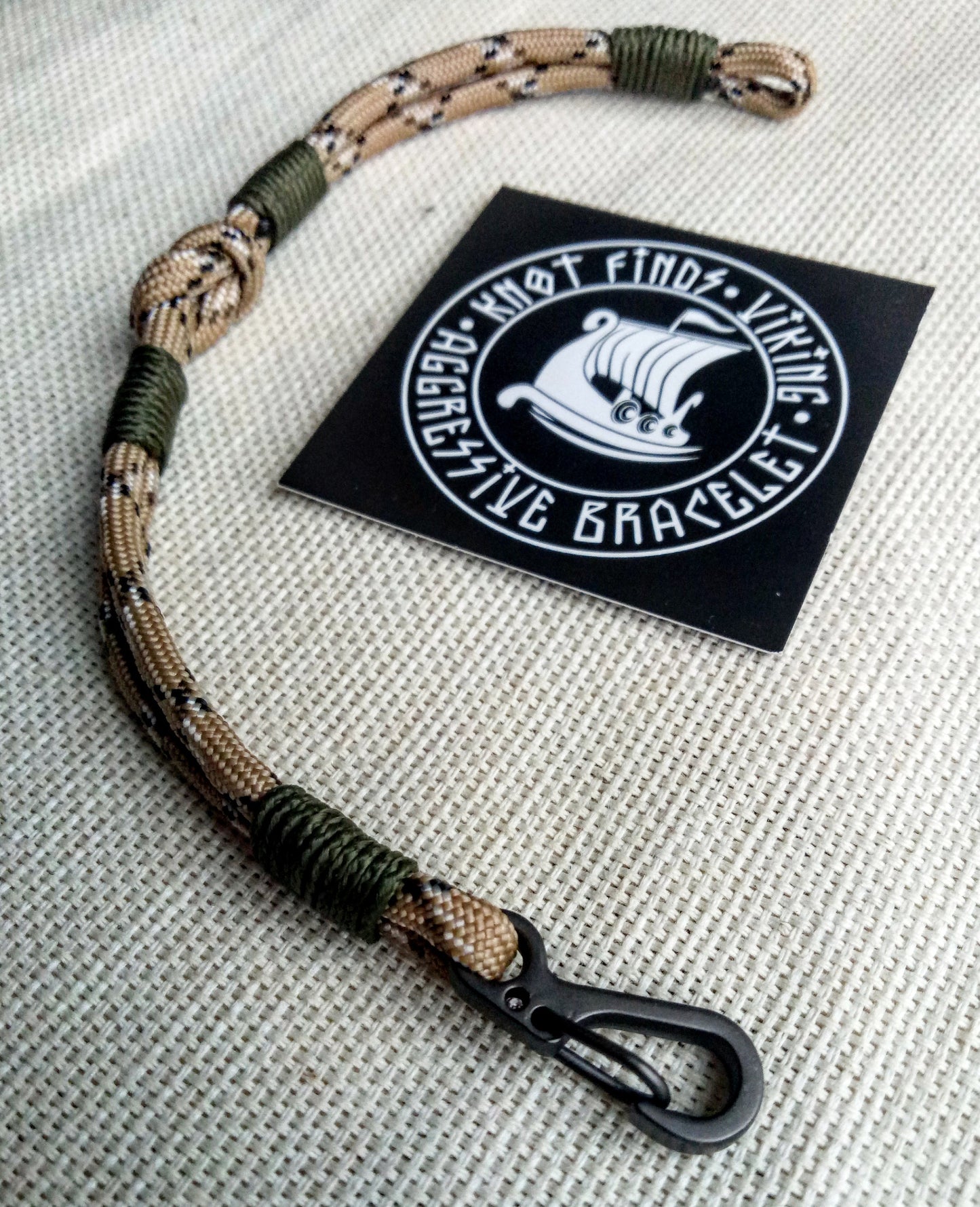 Thin military bracelet made of paracord and carabine for men. Camouflage desert camo. Army style.