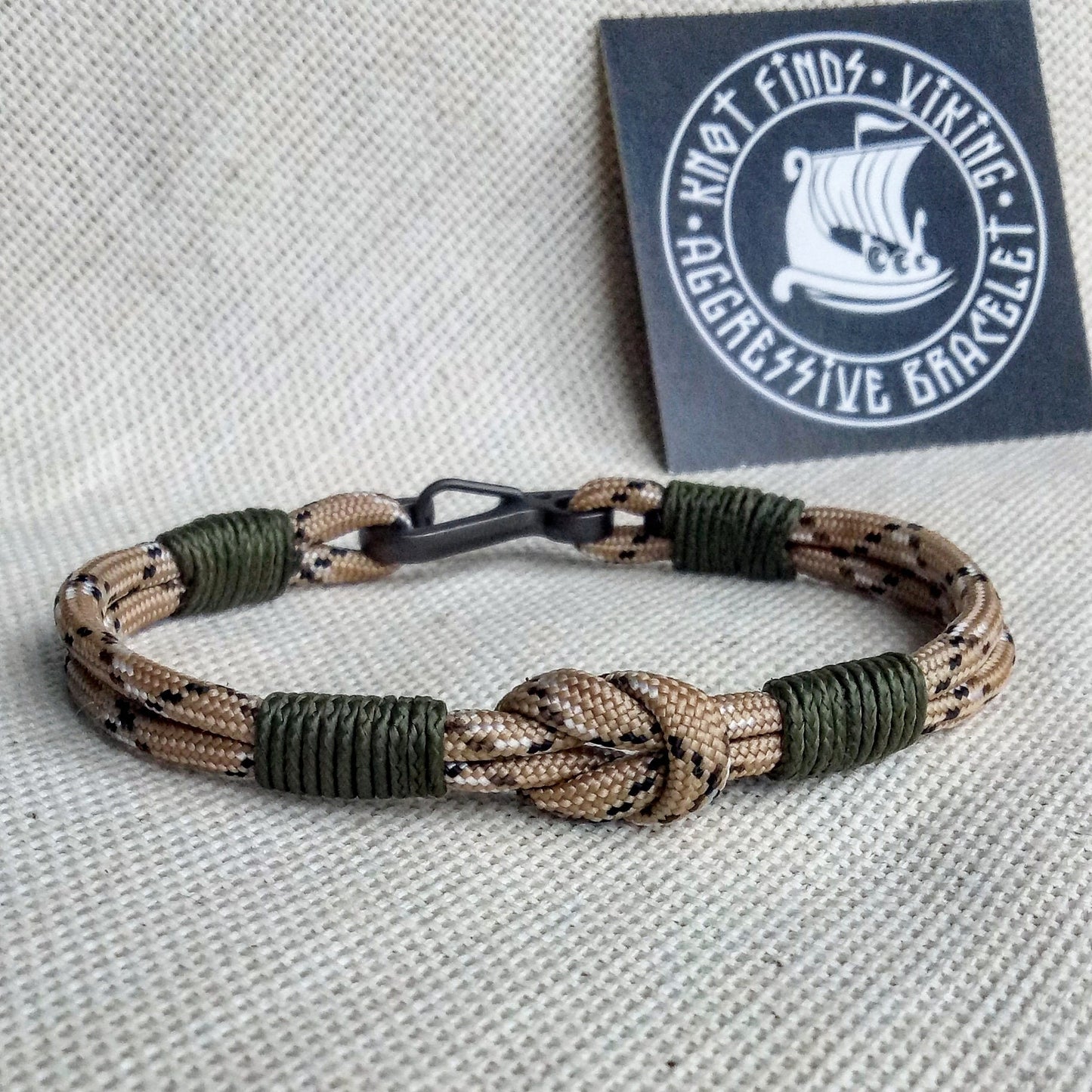 Thin military bracelet made of paracord and carabine for men. Camouflage desert camo. Army style.